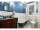 Charming bathroom with vintage-style tub, wainscoting, and blue accent wall at 1419 N Adams St, Denver, CO 80206