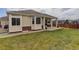 Exterior shot of a home's rear featuring a spacious backyard with manicured lawn and covered patio at 24621 E Berry Pl, Aurora, CO 80016