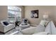 Comfortable living room with neutral tones, tufted seating, and a sunlit window with privacy blinds at 24621 E Berry Pl, Aurora, CO 80016