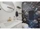 Stylish bathroom featuring a circular mirror, striking wallpaper, and elegant fixtures at 8981 E Amherst Dr # E, Denver, CO 80231