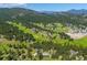 An aerial view of a lush green neighborhood with rolling mountains in the background at 29263 Sue Rd, Evergreen, CO 80439