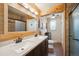 Rustic bathroom featuring wood paneling, a double sink vanity, modern fixtures, and a glass shower enclosure at 29263 Sue Rd, Evergreen, CO 80439