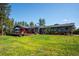 Backyard of home featuring green grass, mature trees, brick accents, and spacious deck at 29263 Sue Rd, Evergreen, CO 80439
