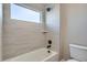 Modern bathroom showcasing light tiles, tub, shower head, and window at 6353 N Fulton St, Denver, CO 80238