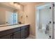 This bathroom features dual sinks, grey cabinets, and a view to a walk in shower at 6353 N Fulton St, Denver, CO 80238