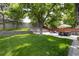 Large, green backyard with a patio, seating, and mature shade trees at 3400 S Ivy Way, Denver, CO 80222