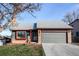 Inviting home exterior featuring a two-car garage, brick accents, and tidy landscaping at 18874 E Mexico Dr, Aurora, CO 80017