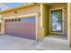 Inviting entryway with a brown garage door, a 'hello' welcome mat, and sconce lighting flanking the front door at 5280 Raritan Way, Denver, CO 80221