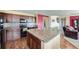 Modern kitchen featuring granite countertops, dark wood cabinets, black appliances, and an open layout with connecting living space at 5280 Raritan Way, Denver, CO 80221