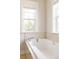 Bright bathroom featuring a soaking tub with tile surround, and natural light from two windows at 7382 E 8Th Pl, Denver, CO 80230