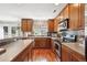 Well-lit kitchen boasts wood cabinets, stone countertops and backsplash, and stainless steel appliances at 9066 Apache Plume Dr # E, Parker, CO 80134