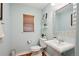Powder room with pedestal sink, wood-look floors, and wall shelves at 9066 Apache Plume Dr # E, Parker, CO 80134