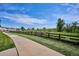 Scenic walking path alongside community homes bordered by grass and a wooden fence at 9066 Apache Plume Dr # E, Parker, CO 80134