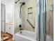 View of the bathroom tub and shower with travertine-style walls, a built-in shelf and a detachable shower head at 11608 Apache Trl, Conifer, CO 80433