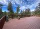 Expansive wooden deck featuring charming wood carvings, lovely flower arrangements, and wooded scenery at 11608 Apache Trl, Conifer, CO 80433