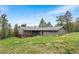 Exterior view of a home with a deck surrounded by lush greenery and a well-maintained lawn at 11608 Apache Trl, Conifer, CO 80433