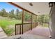 Cozy covered porch with wood flooring and railing overlooks a serene green landscape with scattered trees at 11608 Apache Trl, Conifer, CO 80433