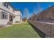 Manicured backyard with artificial turf, a retaining wall, and a partially covered patio offers ample space for outdoor enjoyment at 2702 Rising Moon Way, Castle Rock, CO 80109