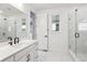 Bright bathroom featuring a double sink vanity, an oversized mirror, marble floors, and a glass enclosed shower at 8601 Yellowcress St, Littleton, CO 80125