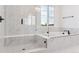 Bright bathroom featuring a glass enclosed shower and soaking tub with white marble tile and black fixtures at 8601 Yellowcress St, Littleton, CO 80125