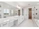 Bright bathroom featuring double sink vanity, an oversized mirror, marble floors, and a glass enclosed shower and tub at 8601 Yellowcress St, Littleton, CO 80125