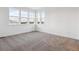 Bright bedroom featuring neutral carpet, white walls and trim, and large windows offering neighborhood views at 8601 Yellowcress St, Littleton, CO 80125