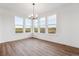 Bright dining room featuring wood-look floors, modern chandelier, and multiple windows looking out on the fenced yard at 8601 Yellowcress St, Littleton, CO 80125