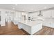 Bright kitchen features an oversized island, stainless vent hood, white cabinets, and wood-look flooring at 8601 Yellowcress St, Littleton, CO 80125