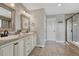 Well-lit bathroom with double sinks, framed mirrors, tile flooring, and glass door shower at 12059 S Tallkid Ct, Parker, CO 80138