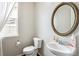 Half bathroom with sink and toilet, natural light and decorated with a circular mirror at 2810 Shadow Dance Dr, Castle Rock, CO 80109