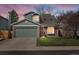 Charming two-story home featuring a two-car garage, brick accents, and a well-maintained lawn under a colorful sky at 5557 S Simms Way, Littleton, CO 80127