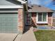 Close-up of home's exterior featuring brick accents, a storm door, and well-maintained lawn at 5557 S Simms Way, Littleton, CO 80127