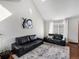 Bright living room featuring two black leather sofas, a patterned rug, and a vaulted ceiling at 5557 S Simms Way, Littleton, CO 80127