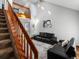 Spacious living room with high ceilings, two black leather sofas, and staircase overlooking the room at 5557 S Simms Way, Littleton, CO 80127