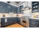 Close-up of a modern kitchen with stainless steel range and backsplash, and shaker cabinets with gold hardware at 1863 Wazee St # 4E, Denver, CO 80202