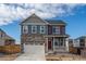 Charming two-story home with a stone facade, white garage door, and red front door at 27664 E Byers Ave, Aurora, CO 80018