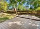 Backyard with a wood deck, fence lined with shrubs, mature trees, and green grass at 13784 W 67Th Way, Arvada, CO 80004