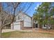 Side view of a two-story home with brick and siding and three-car garage, surrounded by mature trees at 10383 Erin Pl, Lone Tree, CO 80124