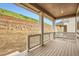 Covered outdoor patio features wood-look decking and white railing with a view of the backyard and retaining wall at 7357 S Yank Ct, Littleton, CO 80127