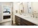 Stylish bathroom with double vanity sinks, dark wood cabinets, and a view into the bedroom at 1236 Castlecombe Ln, Monument, CO 80132