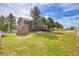 Scenic backyard with a wooden deck and storage shed, surrounded by lush greenery and a white fence at 35675 Cheyenne Trl, Elizabeth, CO 80107