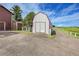 View of the barn with gray siding and a red metal roof at 35675 Cheyenne Trl, Elizabeth, CO 80107