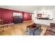 Living room with hardwood floors, red accent wall, with piano and access to dining room at 21354 E 51St Ave, Denver, CO 80249