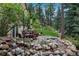 Lush backyard with a stone waterfall feature and patio dining area at 20190 Deer Shadow Way, Monument, CO 80132