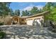 Front exterior of the house featuring a three-car garage, mature trees, and a manicured lawn at 20190 Deer Shadow Way, Monument, CO 80132