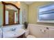 Charming bathroom with wainscoting, pedestal sink, and wood framed mirror at 5886 Urban St, Arvada, CO 80004