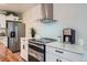 Modern kitchen with stainless steel appliances, white cabinetry, quartz countertops, and a sleek stainless steel range hood at 5886 Urban St, Arvada, CO 80004