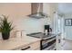 Close-up of a kitchen featuring a stainless steel range hood, electric stove top, and modern white cabinets at 5886 Urban St, Arvada, CO 80004