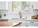 Bright kitchen with stainless steel faucet, white cabinets and countertops, and a view out the window at 5886 Urban St, Arvada, CO 80004