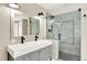 Modern bathroom featuring a double vanity, large mirror, glass shower, and stylish fixtures at 9885 Thornbury Way, Highlands Ranch, CO 80129
